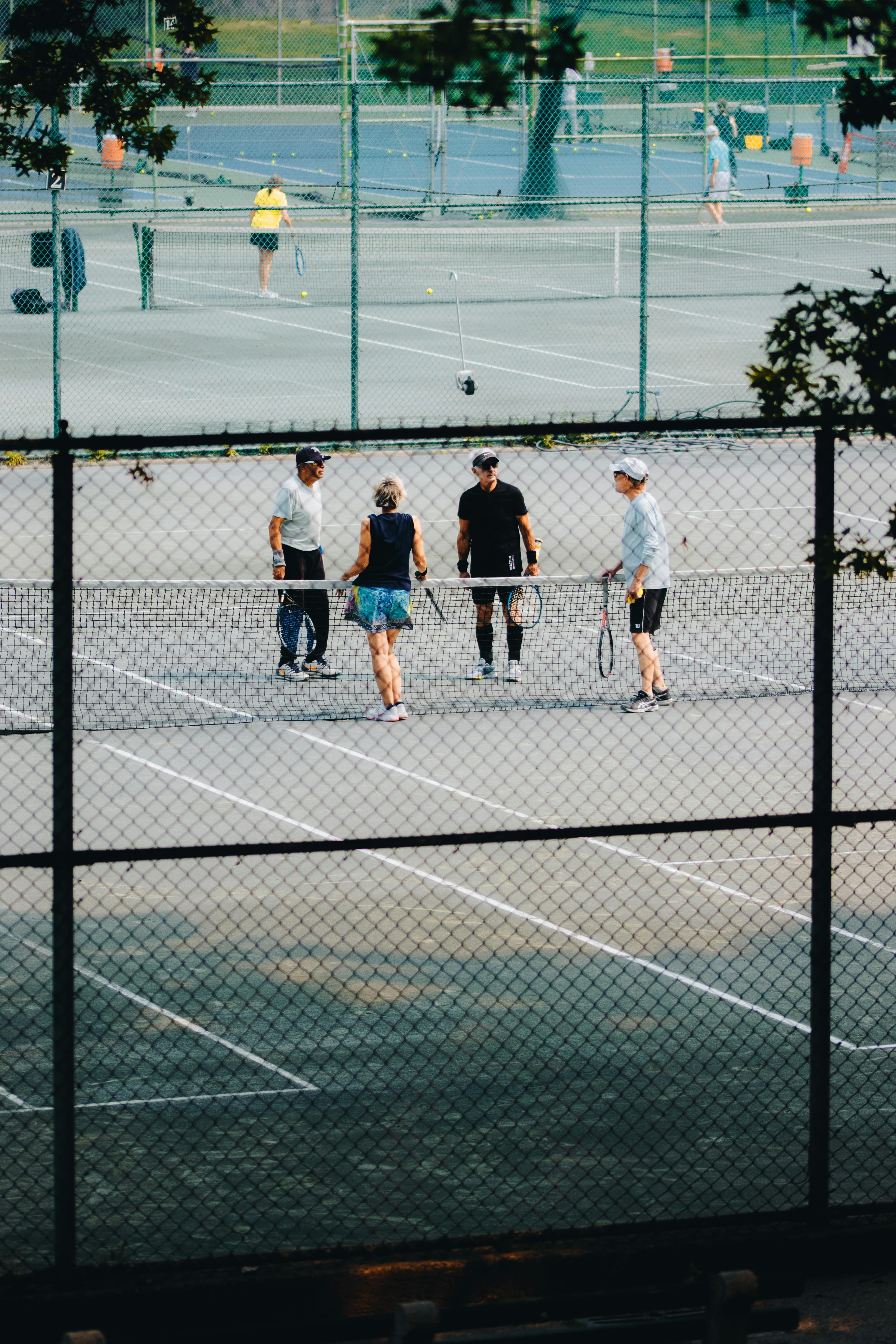 Grupo de personas mayores jugando al tenis en un club